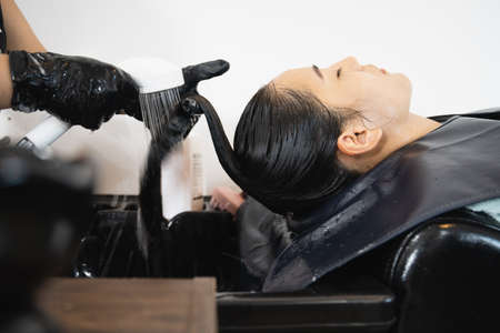Beautiful Asian young woman having a hair care treatment and hair washing service at hair salon.の写真素材