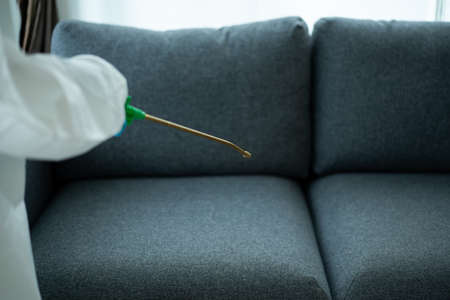 Sanitary staff sanitizing a surface inside the building cause coronavirus or COVID-19 disease pandemic. Cleaning worker using a cleaning chemical spray on the surface to sanitize from COVID19 virus.の写真素材