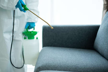 Sanitary staff sanitizing a surface inside the building cause coronavirus or COVID-19 disease pandemic. Cleaning worker using a cleaning chemical spray on the surface to sanitize from COVID19 virus.の写真素材