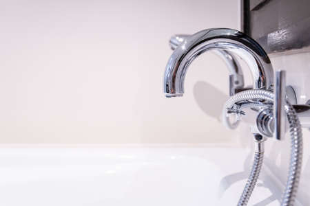 Luxurious silver hot - cold water tap and shower head for bathtub in bathroom close up. Health care and wellness concept.の写真素材