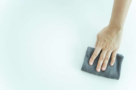 Unrecognizable Asian housekeeper using microfiber wiping on a surface of table close up with...