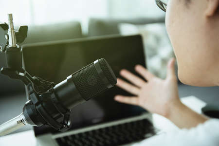 Unrecognizable Asian young man making a home podcast or online radio live streming and looking at laptop or notebook screen. Live streaming and podcast performace.の写真素材