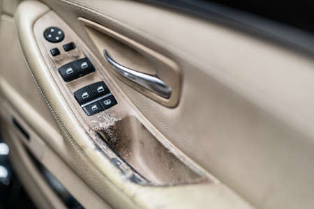Malted and dirty car door hand rail close up. Interior vehicle window control panel and handle was...