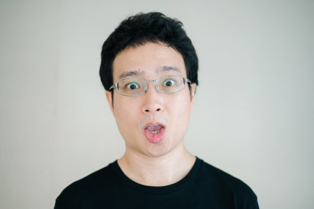 Handsome - happy Asian young man with eye glasses in black shirt portrait on the background. Headshot portrait of Asian young man.の写真素材