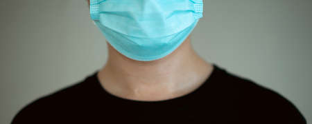 Unrecognizable Asian young man in black shirt wearing a protective face mask looking at camera close up.  .の写真素材