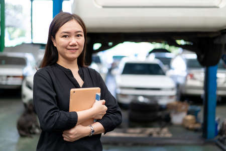 Satisfied Asian young woman in black shirt showing a thumb up in garage.の写真素材