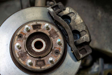Old caliper break and disc break in a vehicle, an old car lifted up on the hydraulic ramp for inspection and maintenance in garage.の写真素材