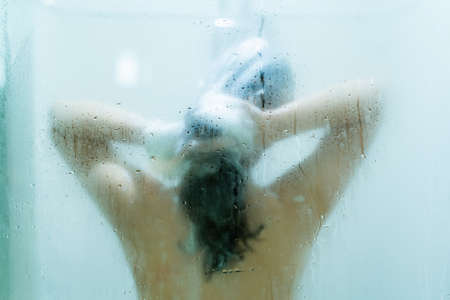 Beautiful Asian woman enjoy taking a shower in the shower room with a drops of water on glass.の写真素材