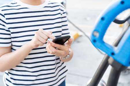 Happy Asian young woman using ev charging application on smartphone connect with the charging...
