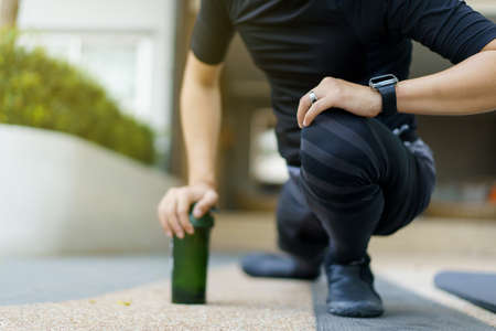 Happy Asian young sportsman doing a lower and upper body stretching before making an exercise in a park, stretching and workout concept. Sport man making a cardio and weight training workout.の写真素材
