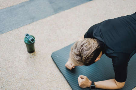 Active Asian young man making an outdoor body weight exercise close up, sportsman doing body weight workout by pushup and plank. Asian sportsman exercising for muscle and body building.の写真素材