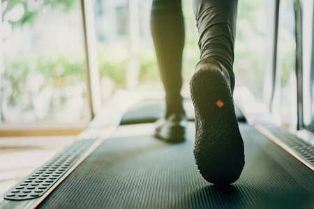 Active Asian sportsman making a cardio exercise by running on the treadmill machine in a fitness or gym, healthy sport man doing a cardio workout.の写真素材