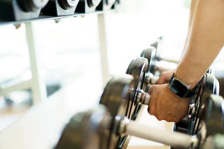 Active Asian sportsman doing a weight exercise in a gym - fitness by lifting up a dumbbell, man...