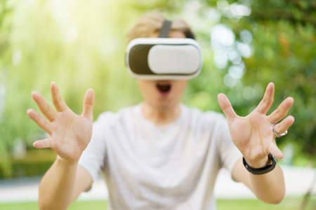Asian handsome young man enjoy interacting with Virtual Reality or VR content by using wireless VR...