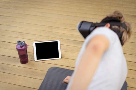 Active sportsman doing a plank exercise and making a video call with a friend and online sport...