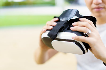 Active Asian sportsman doing a weight training exercise by using dumbbell and virtual reality - VR goggles platform for online training. The innovation of virtual reality or metaverse platform conceptの写真素材