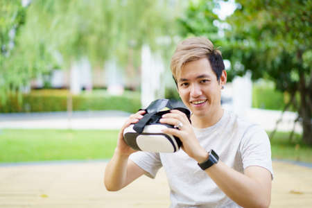 Asian handsome young man enjoy interacting with Virtual Reality or VR content by using wireless VR goggles, Metaverse and virtual reality technology concept. Man watching a content in VR.の写真素材