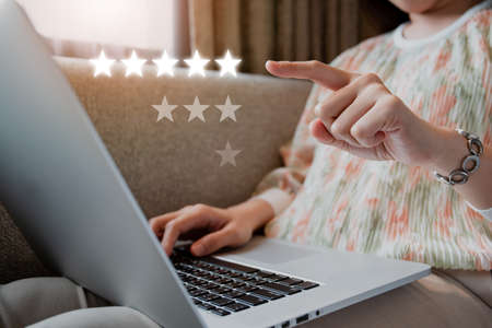 Happy Asian young woman making a video conference on laptop computer while living in the living room, cheerful Asian woman making a gesture or hands sign in video call.の写真素材