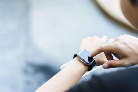 Active Asian young sportsman using a smartwatch or smart fitness band to track his outdoor workout and activities, man reviewing an exercise and health information after finished outdoor workout.の写真素材