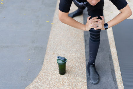 Happy Asian young sportsman doing a lower and upper body stretching before making an exercise in a park, stretching and workout concept. Sport man making a cardio and weight training workout.の写真素材