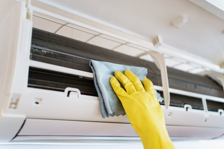 Asian woman cleaning a dirty and dusty air conditioning filter in her house. Housewife removing a dusty air conditioner filter.の写真素材