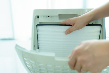 Asian young woman changing - fixing a dirty air purifier HEPA filter after using for a long time. A repairman replacing and installing the air purifier filter. Healthcare and wellbeing.の写真素材