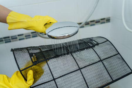 Asian woman cleaning a dirty and dusty air conditioning filter in her house. Housewife removing a dusty air conditioner filter.の写真素材