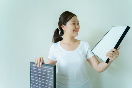 Young woman showing the brand new air purifier filter to camera close up. HEPA filter used in high efficiency air purifier system to purify the dirty or polluted air inside the house or vehicle.の写真素材