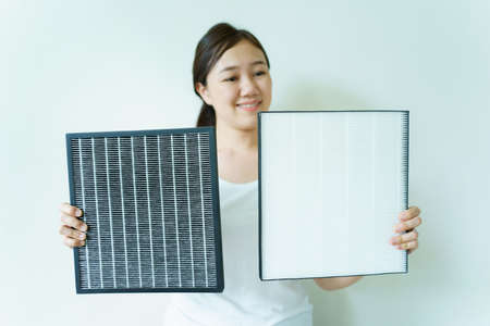 Young woman showing the brand new air purifier filter to camera close up. HEPA filter used in high efficiency air purifier system to purify the dirty or polluted air inside the house or vehicle.の写真素材