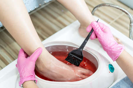 Beautiful Asian young woman having a paraffin foots and hands spa at beauty - spa shop. Foot and hand paraffin treatment.の写真素材