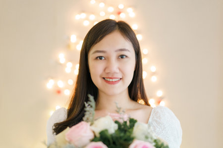 Happy Asian beautiful young woman holding a bouquet of flowers in wedding ceremony. Woman smiling and holding a beautiful flower bouquet in Valentine day or wedding party.の写真素材