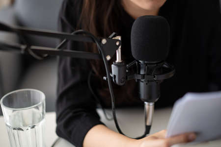 Beautiful and good looking young Asian woman arranging home podcast channel. Businesswoman recording her podcast for her online podcast live on the laptop computer and tablet. Modern working lifestyleの写真素材