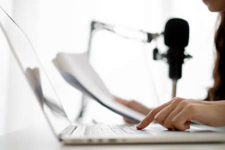 Beautiful and good looking young Asian woman arranging home podcast channel. Businesswoman recording her podcast for her online podcast live on the laptop computer and tablet. Modern working lifestyleの写真素材