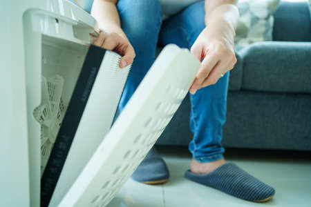 Asian young woman changing - fixing a dirty air purifier HEPA filter after using for a long time. A repairman replacing and installing the air purifier filter. Healthcare and wellbeing.の写真素材