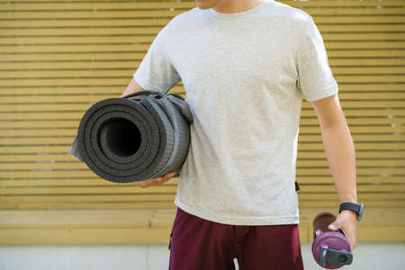 Active Asian sportsman preparing - unrolling an exercise or Yoga mat, healthy and fit body of Asian...