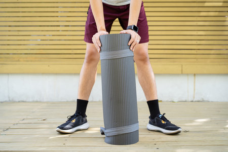 Active Asian sportsman preparing - unrolling an exercise or Yoga mat, healthy and fit body of Asian sport man preparing a workout yoga mat for body weight and cardio exercise.の写真素材