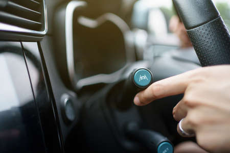 Unrecognizable woman driver activating the adaptive cruise control or steering assistant on the control stick behind steering wheel in electric vehicle - EV car. Driving Assist system in modern car.の写真素材