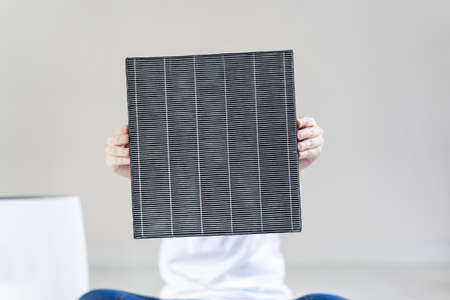 Asian woman wearing a hygiene protective face mask during changing a dirty air filter in the air purifier machine close up with copyspace. Hygienic lifestyle and prevention from illness concept.の写真素材