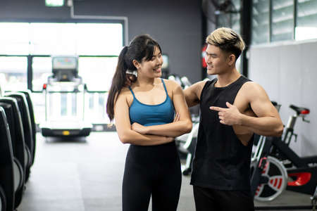 Cheerful healthy Asian sportspeople portrait in a gym with copyspace. Asian young sportswoman and sportsman posing for a photography in a indoor gym. Wellness and wellbeing in healthy people concept.の写真素材