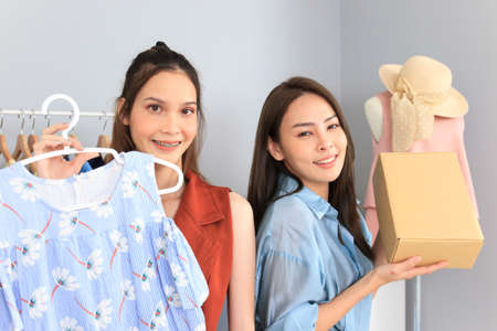 Happy Asian young woman making a live streaming video on social media to sell a beautiful female clothes and lifestyle gadgets. Asian female online merchant streaming a video for sale a clothes onlineの写真素材