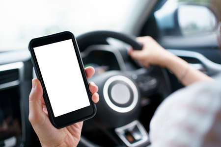 Empty screen smartphone isolated. Unrecognizable careless woman using a smartphone while driving a...
