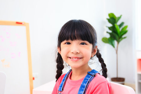 Little happy Asian girl smiling and looking at camera. Innocent little preschool - kindergarten...
