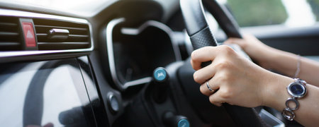 Happy Asian woman driving the electric vehicle - EV car smiling and showing her thumb up to the camera, happy and safety driving concept. Woman driving modern EV car and smiles to camera.の写真素材