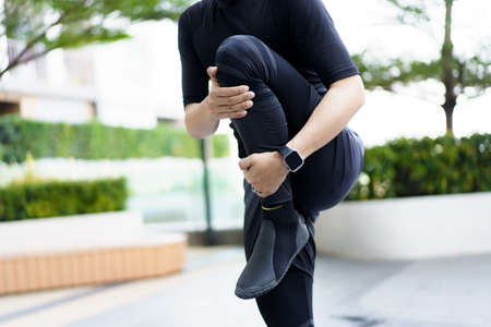Happy Asian young sportsman doing a lower and upper body stretching before making an exercise in a...
