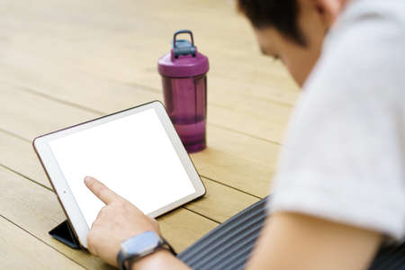 Happy Asian young man doing a plank exercise and watching on a tablet, tablet isolated screen. Man learning and training an exercise online on tablet.の写真素材
