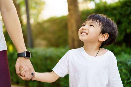 Happy Asian little boy enjoy playing and walking at the park with daddy close up, Asian boy have a beautiful smiling while looking at his father. Little boy portrait at the park anの写真素材