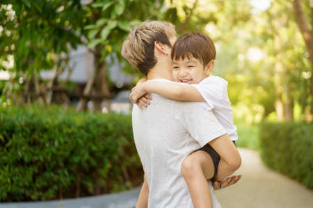 Happy Asian little boy enjoy playing and walking at the park with daddy close up, Asian boy have a beautiful smiling while looking at his father. Little boy portrait at the park and playground.の写真素材