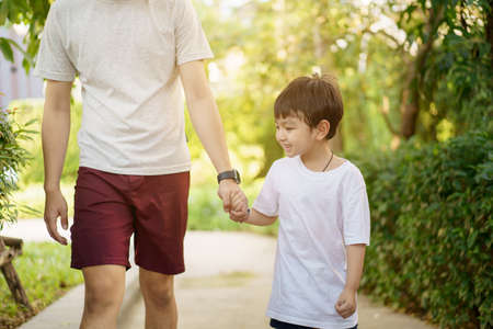 Happy Asian little boy enjoy playing and walking at the park with daddy close up, Asian boy have a beautiful smiling while looking at his father. Little boy portrait at the park and playground.の写真素材