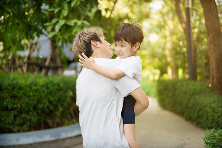 Happy Asian little boy enjoy playing and walking at the park with daddy close up, Asian boy have a beautiful smiling while looking at his father. Little boy portrait at the park and playground.の写真素材