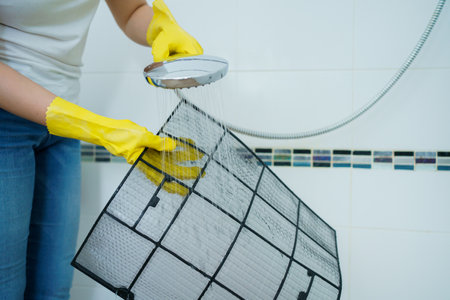 Asian woman cleaning a dirty and dusty air conditioning filter in her house. Housewife removing a dusty air conditioner filter.の写真素材